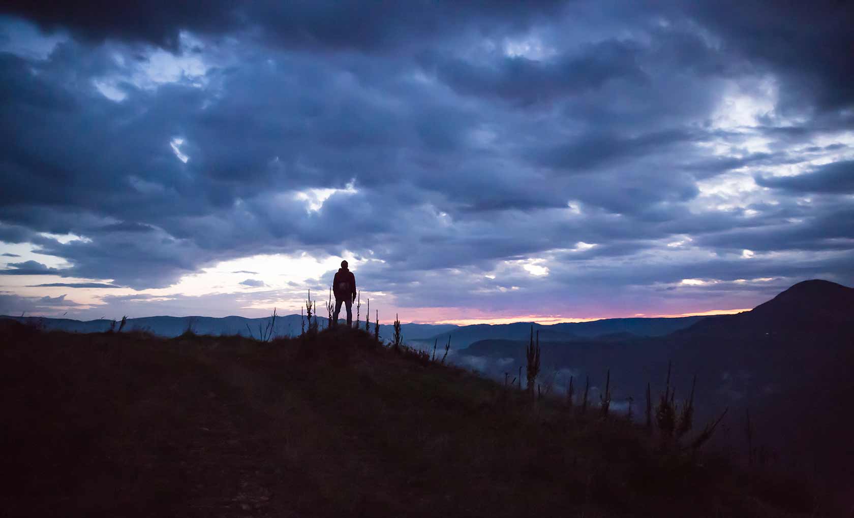 Man on top of hill looking at the horizon. Image 1 of 5.