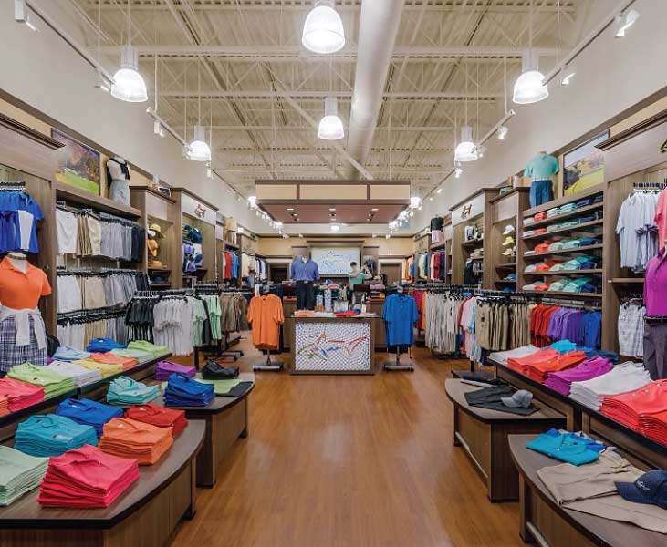 Greg Norman Collection shirts displayed in a store on shelves and tables