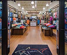 Greg Norman Collection store viewed from the entrance. Shirts are displayed on the walls and tablets in the store.