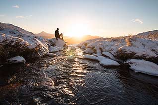 Person sitting on rock in a river